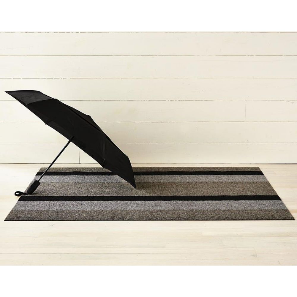 https://www.paletteandparlor.com/cdn/shop/products/chilewich-bold-stripe-shag-door-mat-silver-black-with-umbrella_1000x.jpg?v=1595787663